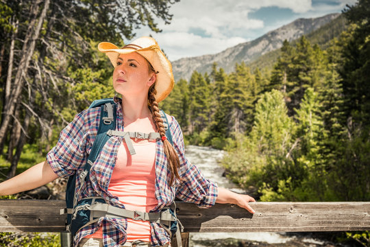 Girl taking a break on a bridge while hiking in the mountains. Red Lodge, Montana, USA