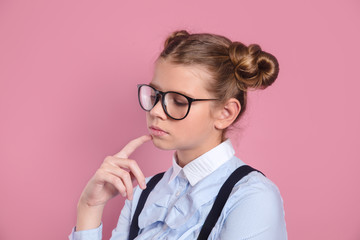 Thoughtful beautiful little girl with intelligent eyeglasses looking away