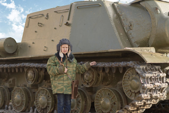 a boy in a tanker uniform near a tank in winter in peacetime in Russia on holiday