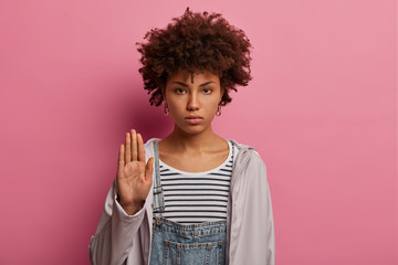 Enough, please. Serious strict woman shows stop gesture, raises palm forwards camera, disagrees and...