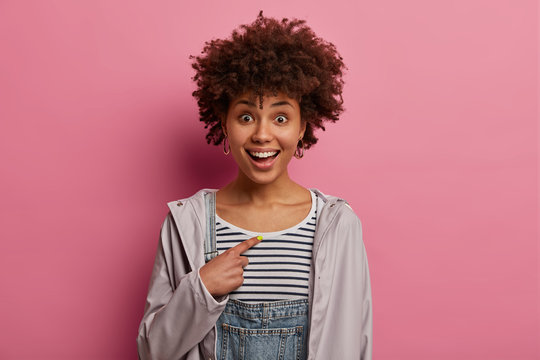 Do you choose me? Lucky positive Afro American woman indicates at herslef, cannot believe in success, feels proud of personal achievements, has amazed face and asks who me, models indoor alone