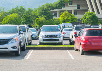 Car parked in asphalt parking lot and one empty space parking  in nature with trees and mountain background