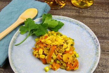 Close up of thai fried rice dish with eggs, peas, sweet corn, shrimps and carrots on wood table