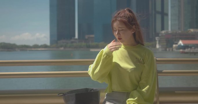Asian Chinese girl coughing due to flu and wearing a surgical face mask to protect herself from COVID-19 coronavirus infection in public crowded places and avoid disease spread