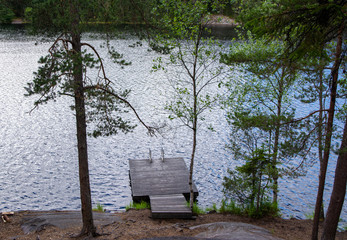 View to the wooden swimming pier and The Lake Hynkanlampi from the forest in summer, Nuuksio, Espoo, Finland