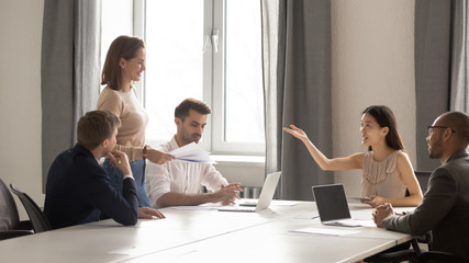 Female employee share handouts to colleagues at briefing