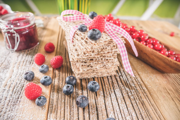 Decorated pastry sweet breakfast with berries and toast over wooden table.