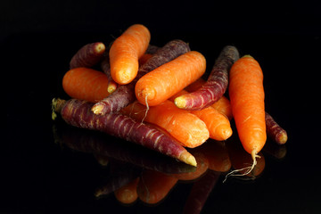 Black carrots and orange carrots over black background