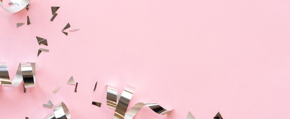 close up on group of silver color of rolling ribbon and confetti on pink background with copy space...