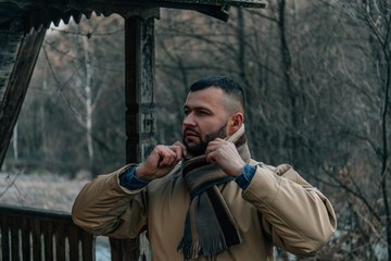 Young handsome man in autumn outdoor setting wearing fashionable clothing. Fashion model posing in autumn scenery.