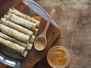 Pancakes with honey on a brown wooden rustic table. Pour pancakes with honey from a spoon. Background for Shrovetide.