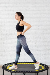 Relaxed woman jumping on trampoline.young fitness girl trains on a mini trampoline in the Studio