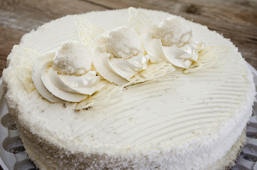 tasty, white cake with cream on a wooden background. Close-up.