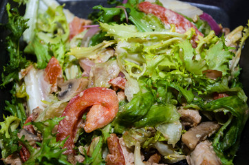 delicious salad with arugula, herbs, meat and tomatoes. Close-up.