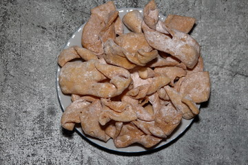 Traditional Polish sweets cake with fancy shape called faworki in Polish usually served on Fat Thursday, close up isolated on stony background flat lay
