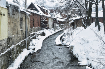 Creek flowing through a mountain village on a cold and snowy winter day