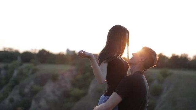 A couple in love enjoys a beautiful sunset. A young and romantic couple is enjoying each other on a romantic summer evening. Happy couple talking and hugging at sunset