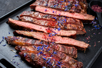 Modern design barbecue dry aged wagyu flank steak offered with herb and salt as closeup on a modern design tray