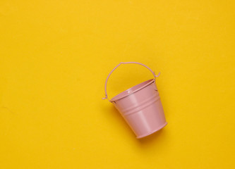 Pink empty mini bucket on yellow background. Minimalism. Trend color concept. Top view