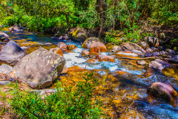 A stream rushing around rocks down a mountain