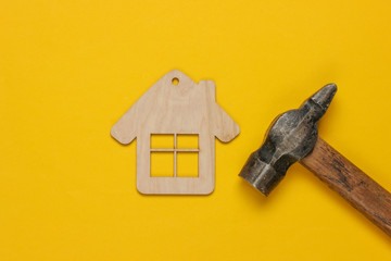 How to build a house? DIY concept. Hammer and mini house figurine on yellow background