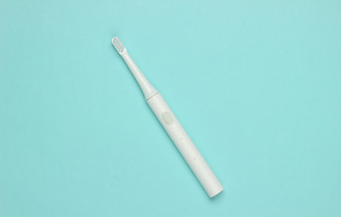 Modern electric toothbrush on a blue pastel background. Dental care concept. Top view. Minimalism
