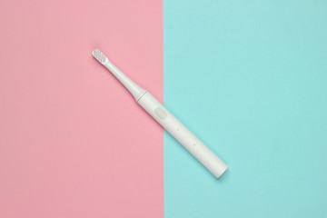 Modern electric toothbrush on a blue pink pastel background. Dental care concept. Top view. Minimalism