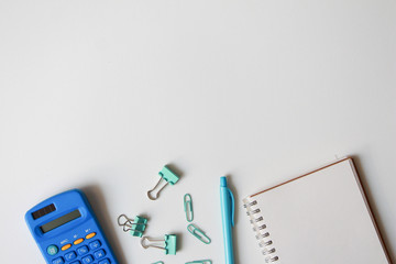 Stationary school supplies in white and blue tone, Scissors, pencils, paper clips,calculator, notepad  on blue and white background, Flat lay.copy space for product or text.