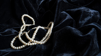 Pearl beads on a beautiful black velvet. Black background.