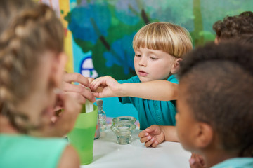 Happy little boy having fun with his friends at playroom. Chemical experimens at kids party.