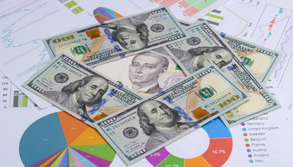 Economic forecast of growth and fall of the currency. Dollar bills and Ukrainian hryvnia among graphs and charts