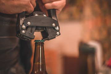 Detail of a tool for closing or bottling beer bottles. Man closing a beer bottle with a cap. Tool for closing craft beer bottle.