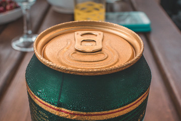 Top of the can of cold beer with drops of water or moist on it. Background of a garden party or...