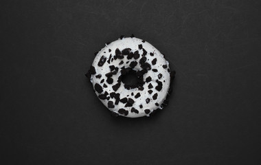 Glazed donut sprinkled with chocolate pieces on black background. Sweets cake, unhealthy food. Top...