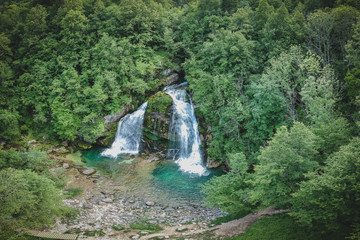 Aerial panorama of magical looking Virje waterfall in Slovenia, close to bovec. Dreamy and enchanting water falling down the cliff above the small alpine lake.