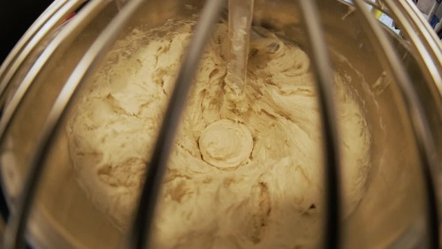 Close-up of dough mixing in a professional kneader machine in kitchen of bakery or at the manufacturing. Stock footage. Dough making process