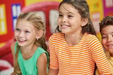 Cute happy little girl. Joyful kids smiling in playroom. Children watching show at entertainment center.