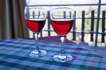 two glasses of Sicilian red wine on the table covered with checkered tablecloth