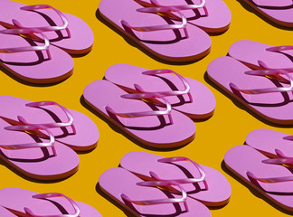 Beach vacation, summer background. Pop art style. A lot of pink flip flops on a yellow background. Fashion shot with shadows.
