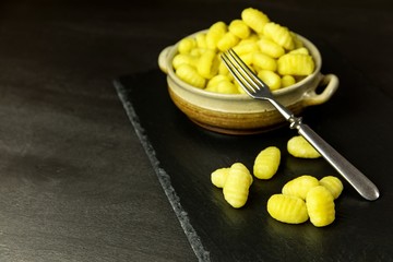 Uncooked homemade gnocchi on black slate board.  Traditional folk food. Potato gnocchi.