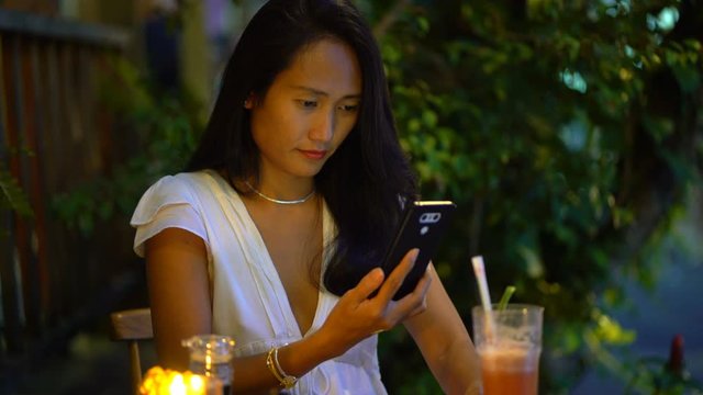 Young asian woman taking photo of drink with cellphone in cafe