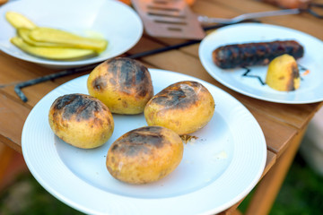 bbq grill cooked potatoes and sausages in backyard in england uk