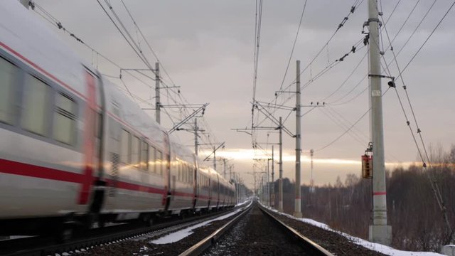 Train rides on rails, sunset sky in the background