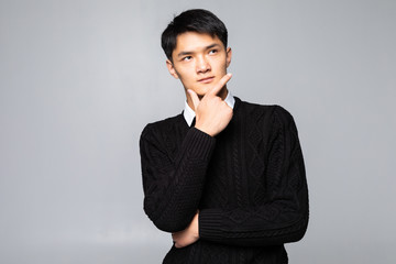 Young asian chinese man with hands on chin standing over isolated white background