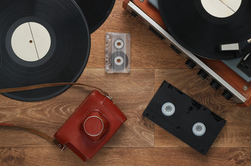 Old vinyl record player, video cassettes, audio cassette, old-fashioned film camera on the floor....