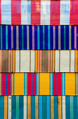 Bold colours in cultural and etchnic patterns on fabric pinned to board. Vibrant and colourful stripes horizontally.