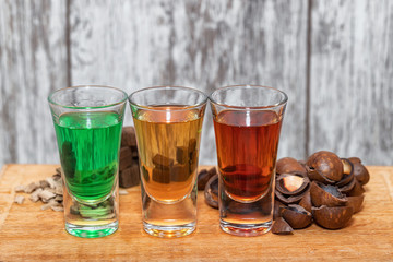 Three shots with different alcoholic beverages stand on a wooden stand