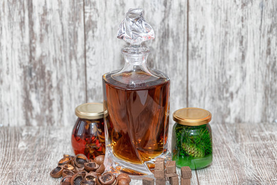A curved crystal decanter with homemade moonshine stands on a wooden stand