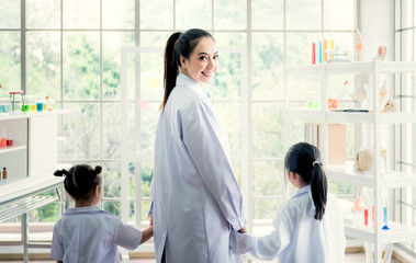 Fototapeta premium Portrait images of pretty Asisn female teacher Holding hands to kindergarteners In the classroom know and experiment in science, to education and children concept.