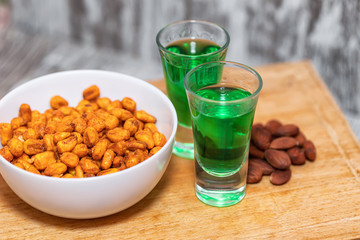 Two shot of absinthe stand on a wooden board.
